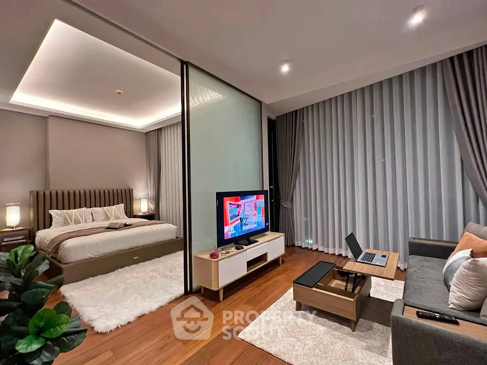 Modern studio apartment with cozy living area and elegant bedroom separated by glass partition.
