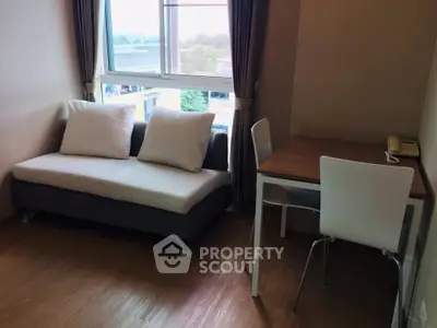 Cozy living room with sofa and dining table, featuring large window with scenic view.