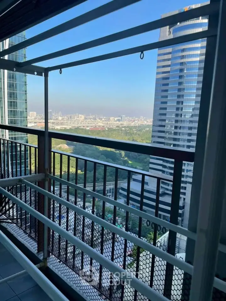 Stunning cityscape view from a high-rise balcony with modern railings and lush greenery below.