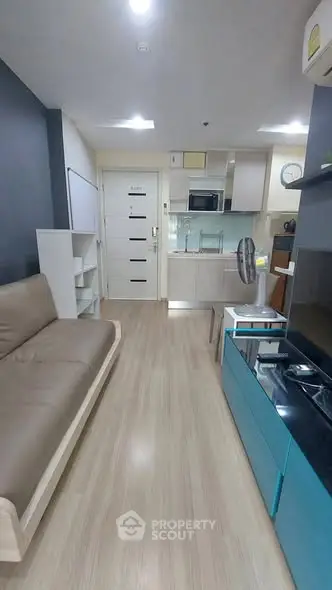 Modern living room with open kitchen layout, featuring sleek furniture and contemporary design.