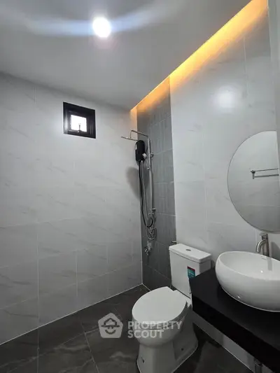 Modern bathroom with sleek design, featuring a round mirror, stylish sink, and contemporary shower setup.