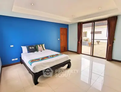 Spacious bedroom with blue accent wall and large windows opening to a patio.