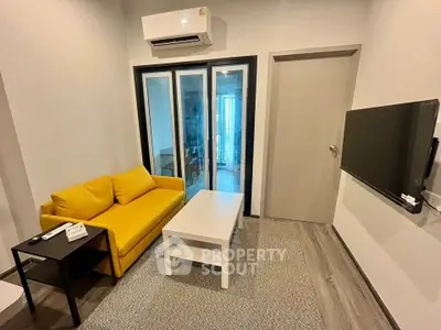Modern living room with yellow sofa, air conditioning, and wall-mounted TV in cozy apartment.