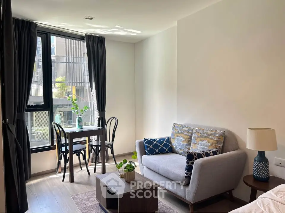 Chic modern living room with cozy sofa and dining area, flooded with natural light from large windows.
