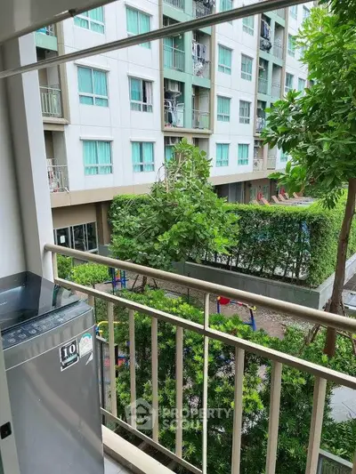 Modern apartment balcony with lush garden view and outdoor amenities.