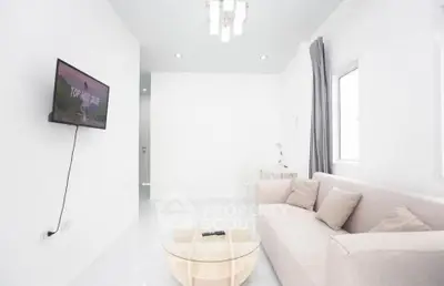 Bright minimalist living room with modern sofa and wall-mounted TV, perfect for relaxation.