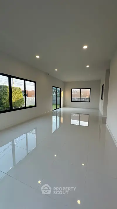 Spacious modern living room with large windows and glossy white flooring.