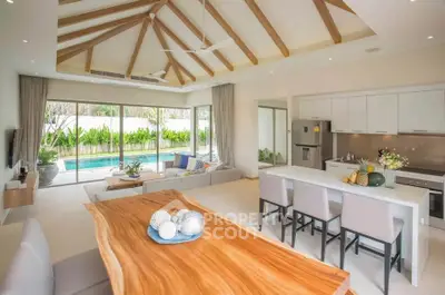 Luxurious open-plan living room with pool view, high ceilings, and modern kitchen in a tropical setting.