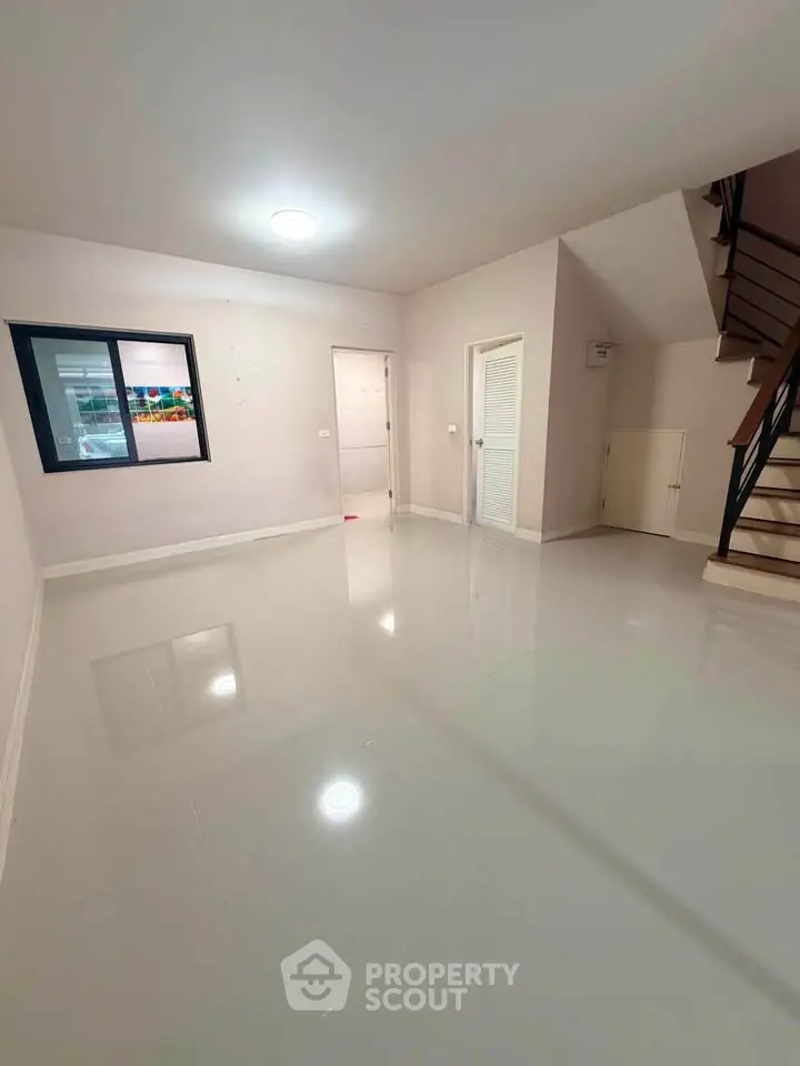 Spacious modern living room with sleek flooring and staircase, perfect for contemporary living.