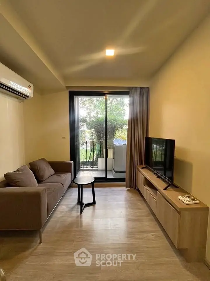 Cozy living room with balcony view, modern sofa, and TV setup.
