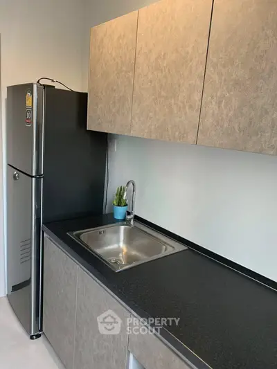 Modern kitchen with sleek cabinetry and stainless steel fridge in a stylish apartment.