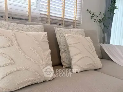 Elegant living room with cozy beige sofa and decorative pillows, perfect for relaxation.