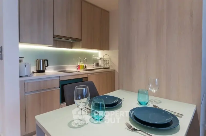 Modern kitchen with sleek cabinetry and dining setup in a cozy apartment.