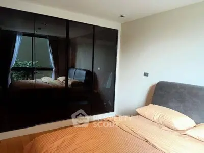 Modern bedroom with sleek mirrored wardrobe and cozy bedding in a stylish apartment.