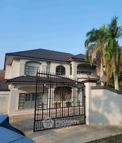 Stunning two-story house with gated entrance and palm trees, perfect for luxurious living.