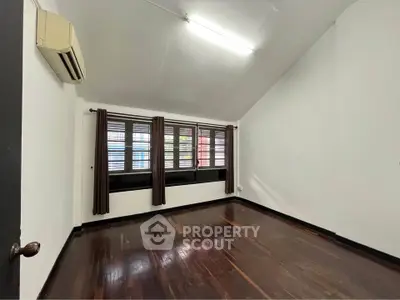 Spacious room with wooden flooring and large windows, perfect for natural light.