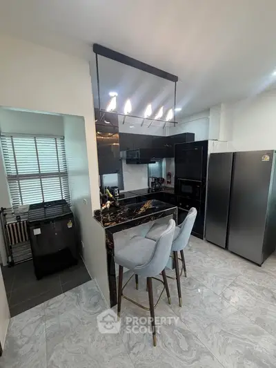 Modern kitchen with sleek black cabinetry, marble countertop, and stylish bar stools.