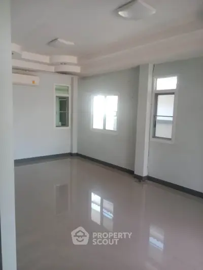 Spacious empty room with glossy tiled floor and large windows
