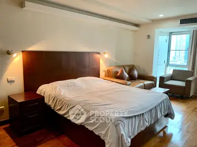 Spacious bedroom with cozy seating area and modern lighting