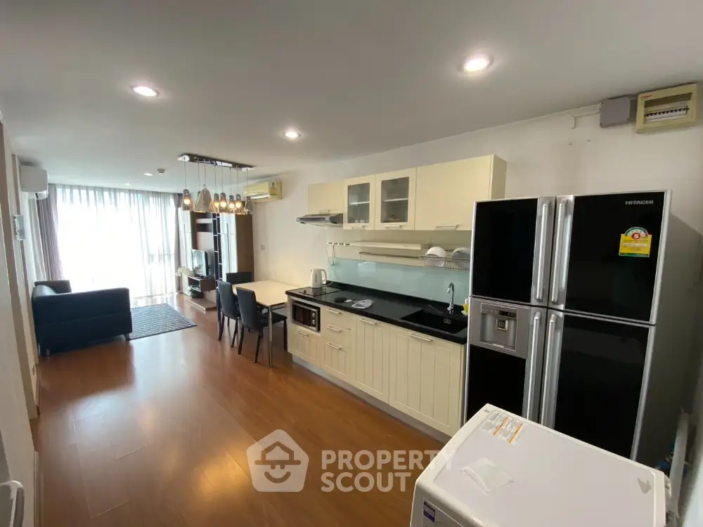 Modern open-layout kitchen and living room with sleek appliances and hardwood floors