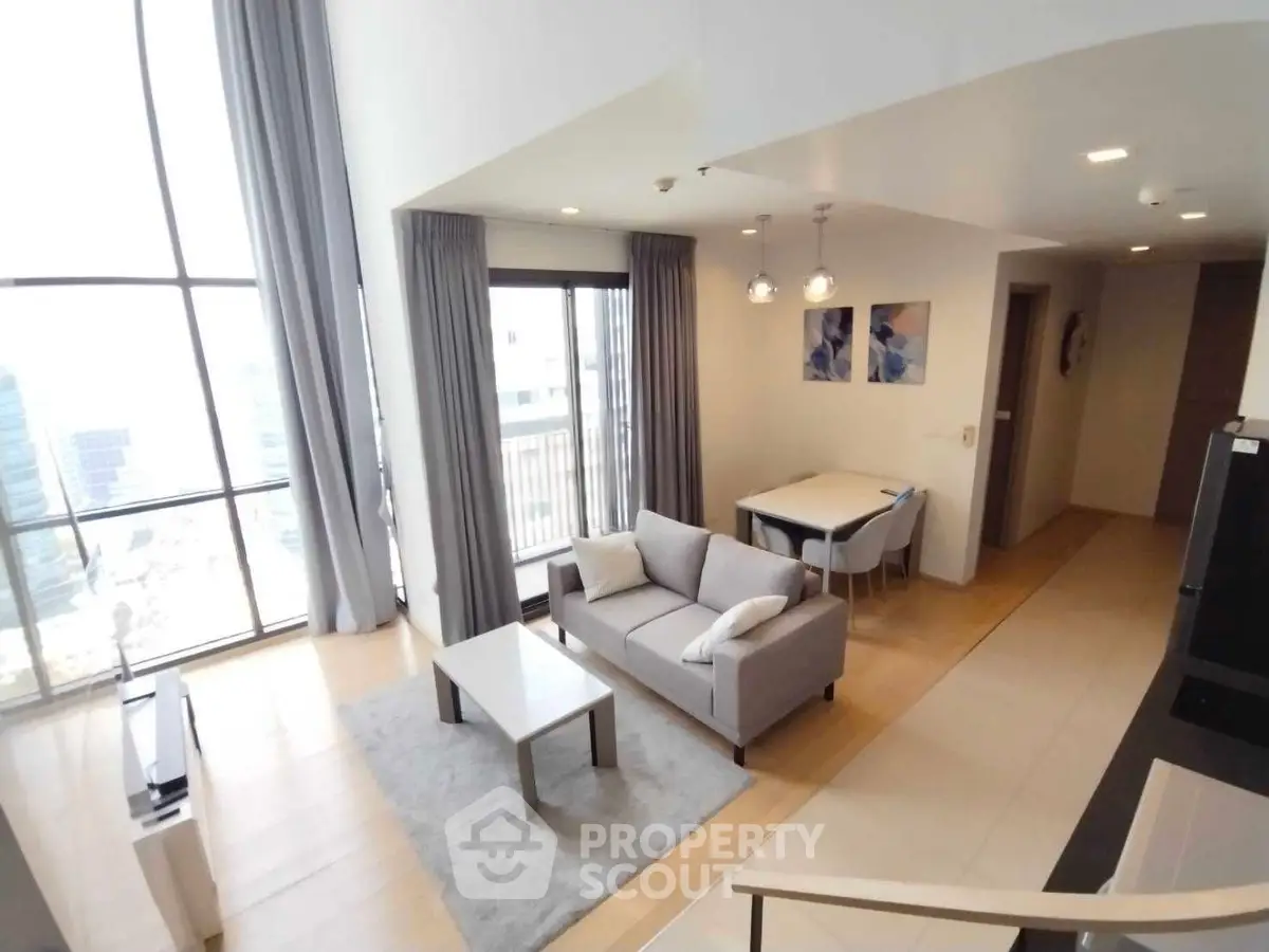 Spacious modern living room with high ceilings and large windows offering city views.