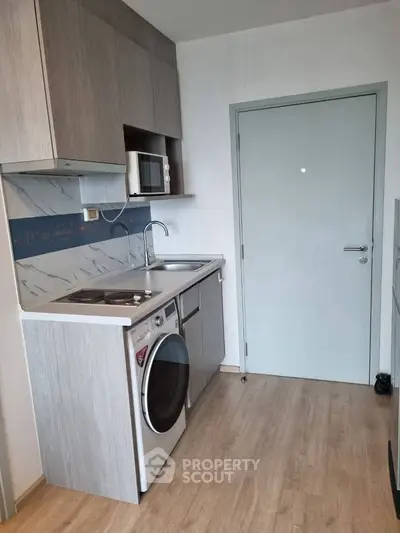 Modern compact kitchen with sleek cabinetry and built-in appliances in a stylish apartment.