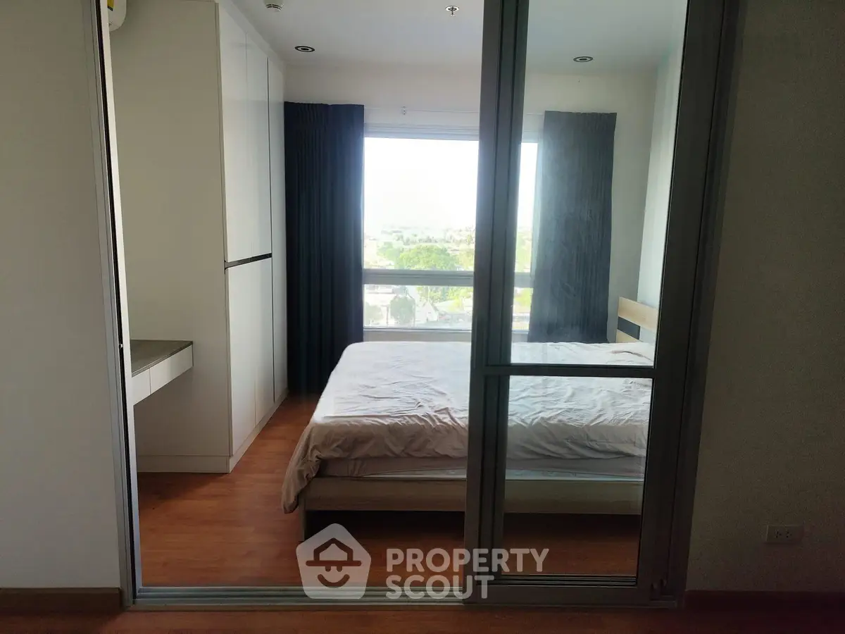 Cozy bedroom with large window offering natural light and scenic view, featuring modern sliding glass door.