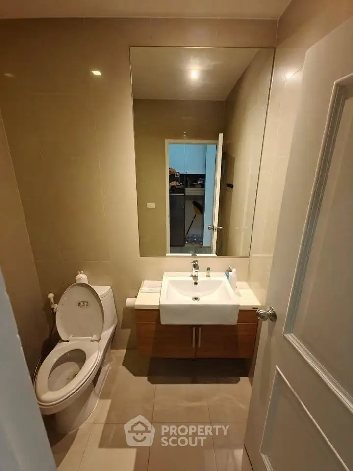 Modern bathroom with large mirror and sleek fixtures in a contemporary home.
