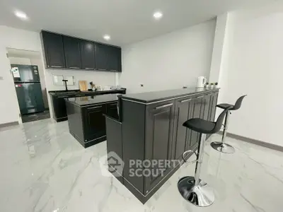 Modern kitchen with sleek black cabinetry and marble flooring