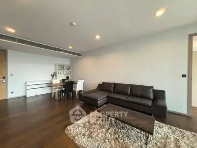 Spacious modern living room with elegant dark leather sofa and chic dining area.
