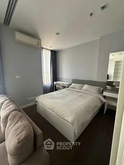 Modern bedroom with sleek design, featuring a comfortable bed, stylish sofa, and ample natural light.