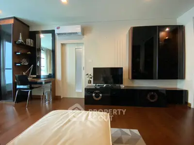 Modern living room with sleek black furniture and wooden flooring, featuring a cozy study nook and air conditioning.