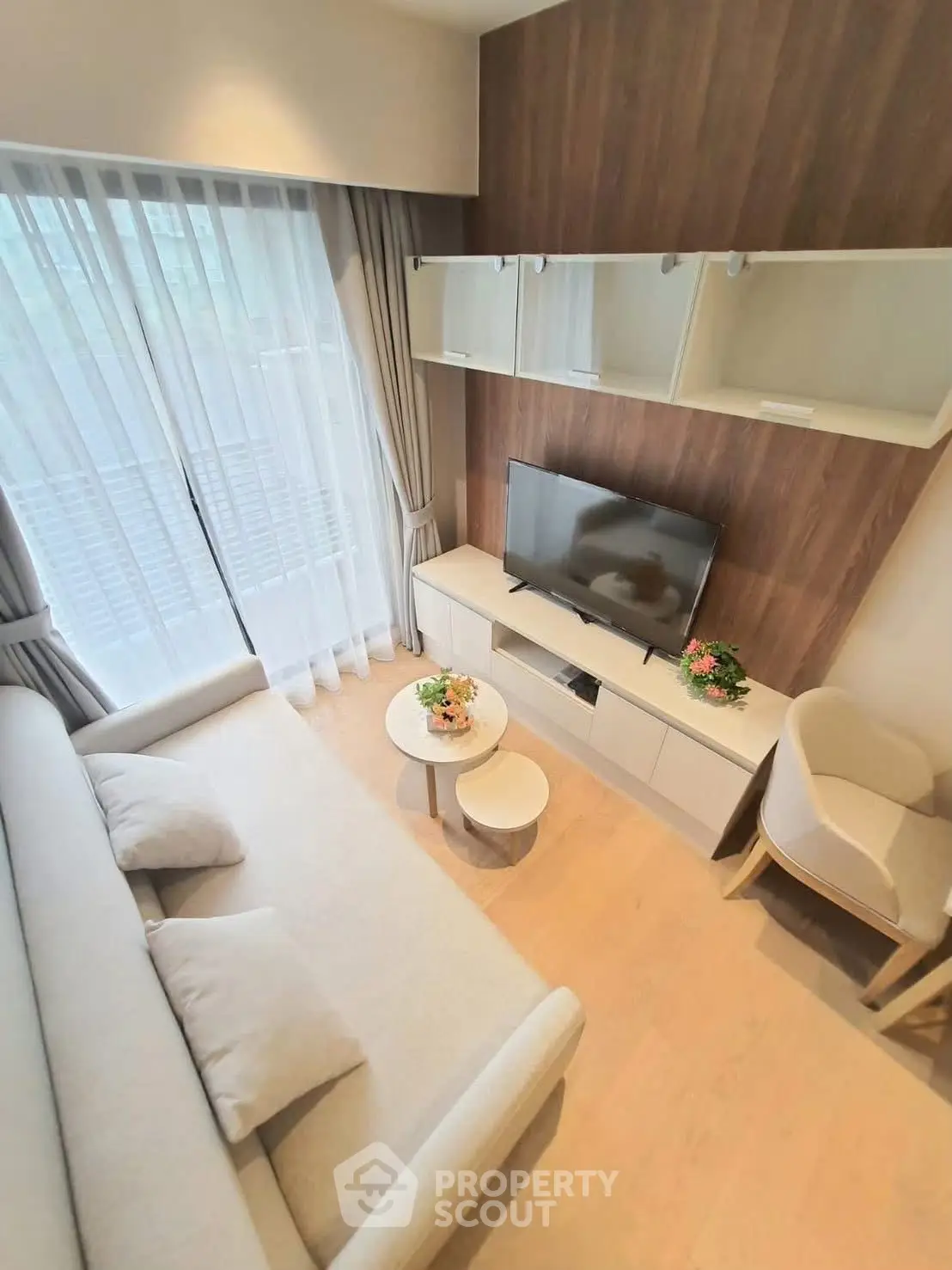 Modern living room with cozy sofa and TV, bright natural light from large window.