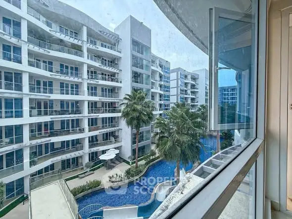 Modern apartment complex with pool view from window, showcasing luxury living.