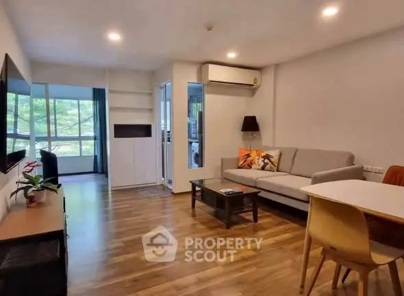 Modern living room with wooden flooring, stylish furniture, and large windows offering a serene view.