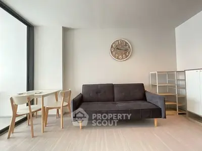 Modern living room with sleek sofa and dining set, featuring minimalist design and neutral tones.