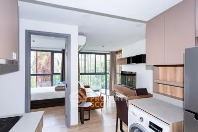 Modern apartment interior with open kitchen and living room, featuring large windows and a washing machine.