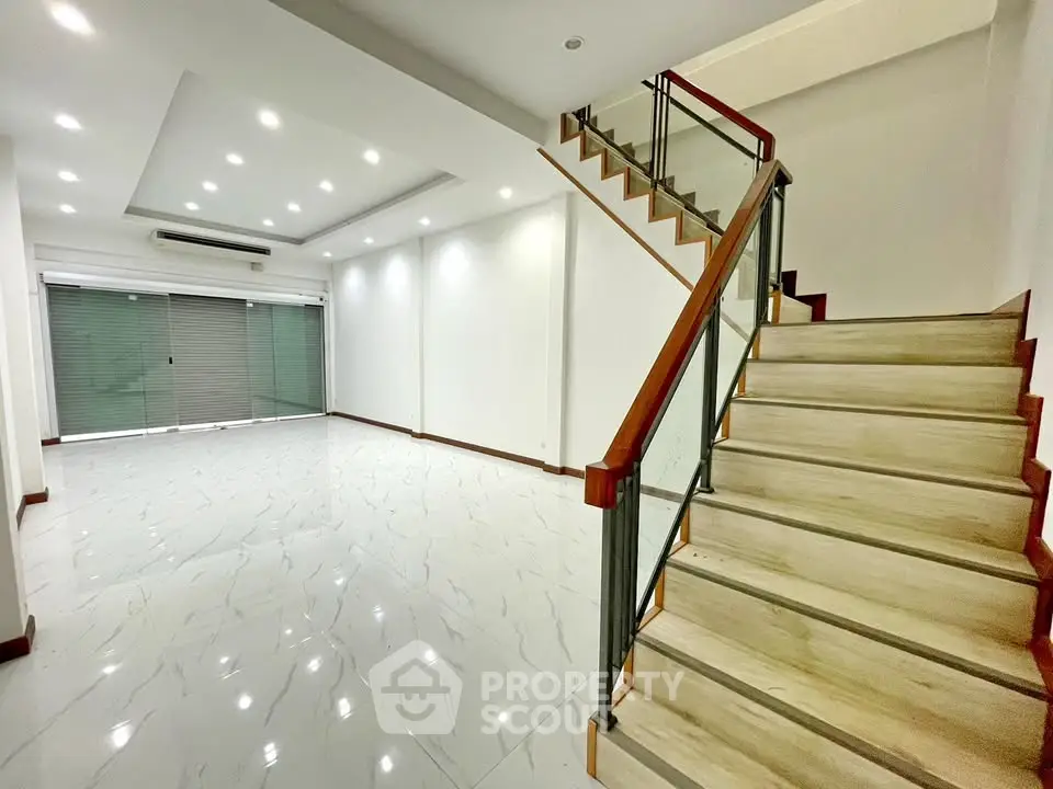 Spacious modern living room with elegant staircase and sleek tile flooring