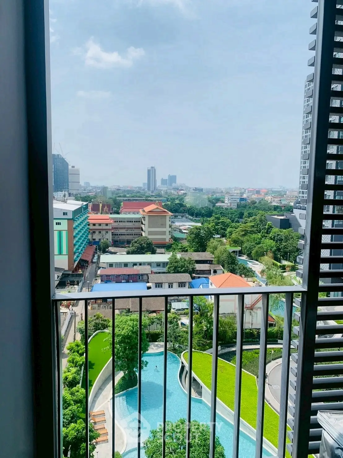 Stunning high-rise balcony view overlooking cityscape and pool area, perfect for urban living.