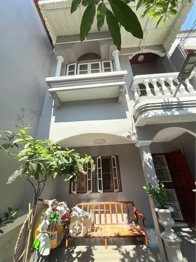 Charming two-story house with balcony and cozy outdoor seating area, perfect for relaxation.