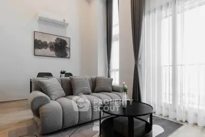 Modern living room with plush sofa, stylish decor, and large windows for natural light.