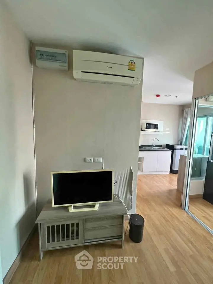 Modern apartment interior with air conditioning and open kitchen layout, featuring sleek appliances and wooden flooring.