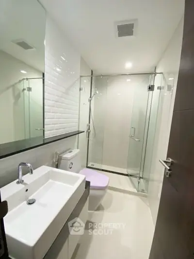Modern bathroom with glass shower and sleek white fixtures