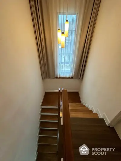 Elegant staircase with wooden steps and modern pendant lighting in a stylish home interior.