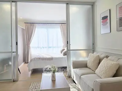 Modern studio apartment with cozy living area and stylish bedroom separated by sliding glass doors.