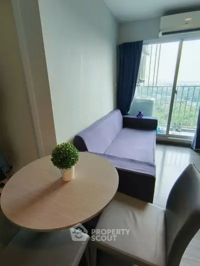 Cozy living room with modern sofa and balcony view in a high-rise apartment.