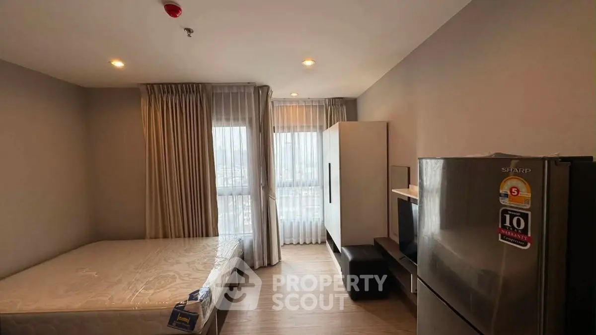 Modern studio apartment with natural light and sleek furnishings, featuring a cozy bed and stylish appliances.