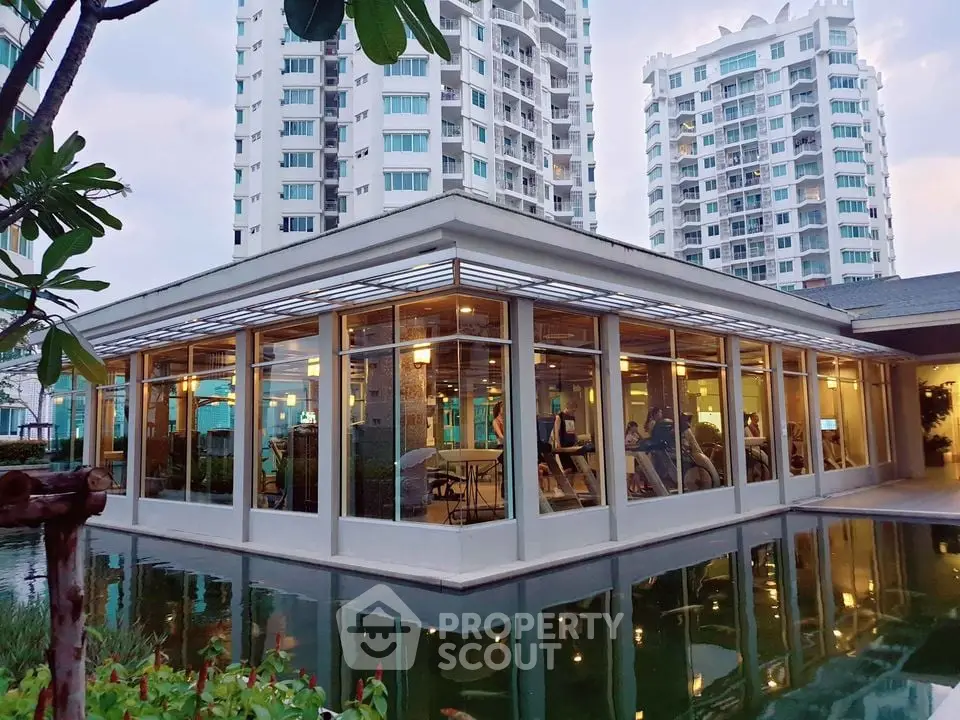 Modern building with glass walls surrounded by a serene water feature and lush greenery.