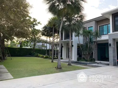 Luxurious modern villa with expansive manicured lawn, tall palm trees, and a grand entrance, showcasing an opulent lifestyle in a serene setting.