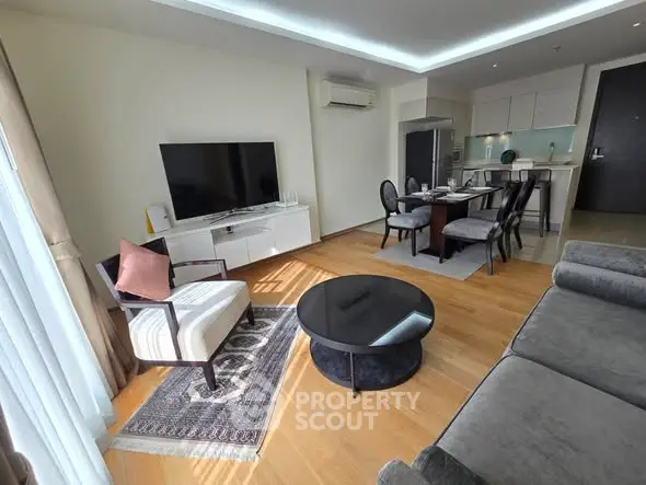 Modern living room with open kitchen, featuring sleek furniture and natural light.